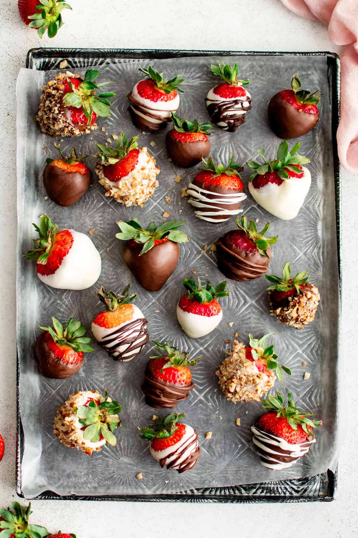 An assortment of chocolate covered strawberries on a cookie sheet