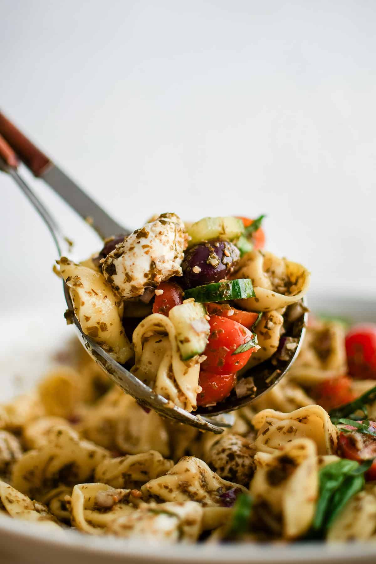 tortellini pesto salad in a serving spoon